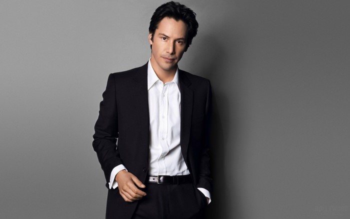 Keanu Reeves in a black suit and white shirt