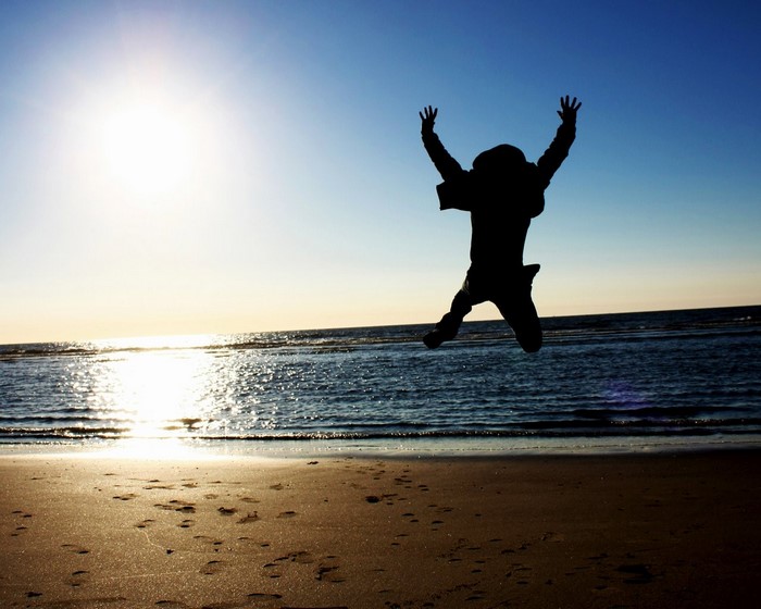 Silhouette of a person jumping on a beach at sunset