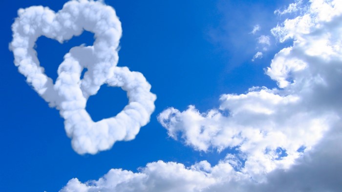 Two heart-shaped clouds intertwined in a blue sky