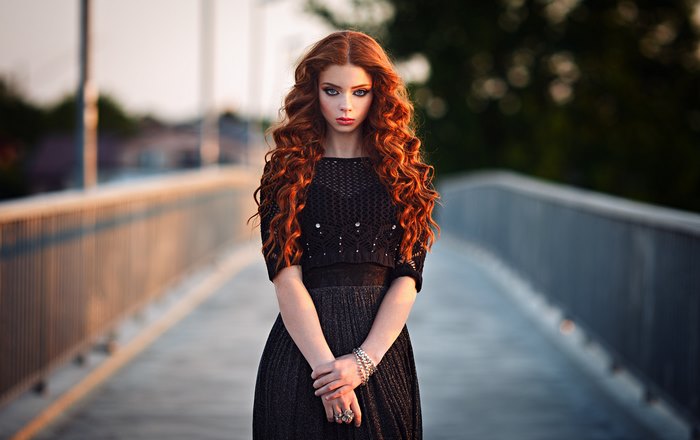 Redhead woman with long curly hair in a black dress