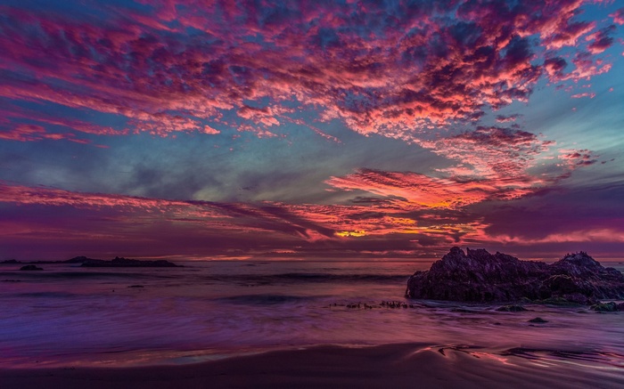 Dramatic sunset over the ocean with colorful clouds and rock formations