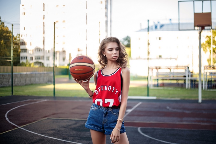 Woman in Detroit basketball jersey holding a basketball