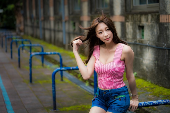 Asian woman with long brown hair in pink top and denim shorts