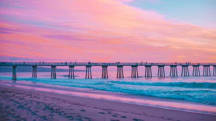 Pier over the ocean at sunset with pink sky