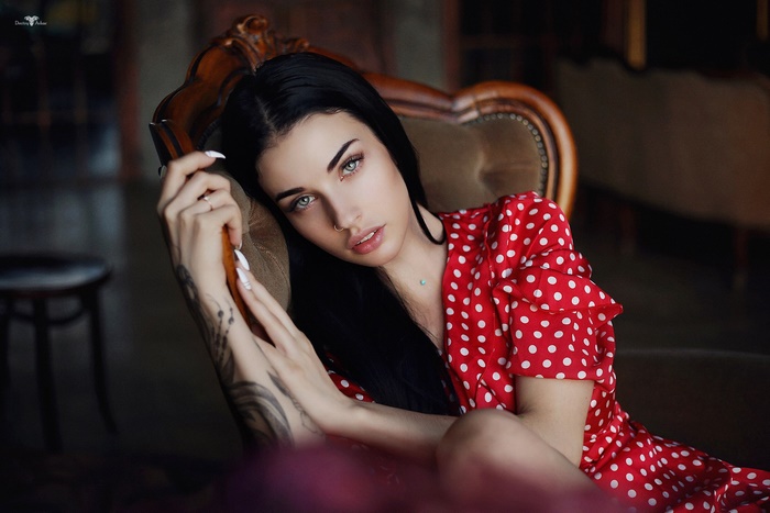 Woman with black hair and blue eyes in a red polka dot dress