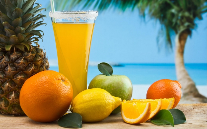Summer fruits and juice on a beach background
