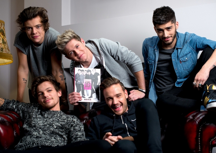 One Direction band members posing with album