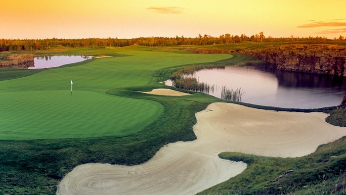 Golf course with water hazards and sand traps at sunset