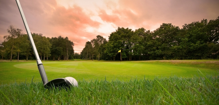 Golf club and ball on a golf course at sunset