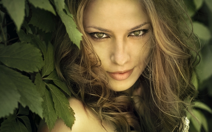 Woman with green eyes and brown hair surrounded by leaves