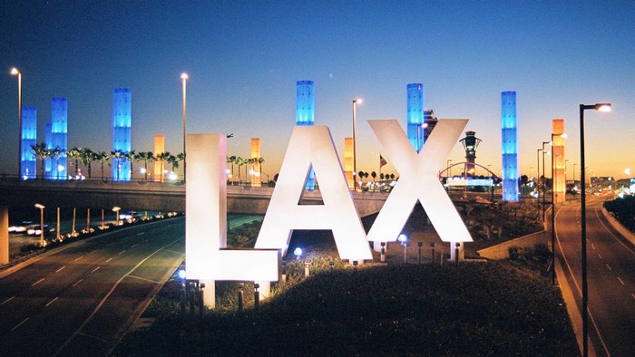 LAX airport sign at dusk with illuminated towers