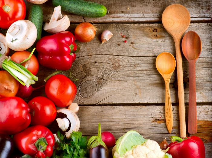 Assortment of fresh vegetables and wooden spoons on a rustic table