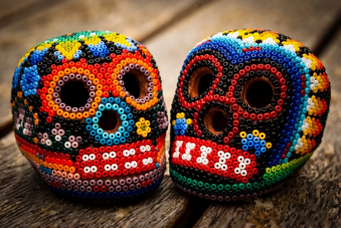 Two colorful beaded sugar skulls on wooden planks
