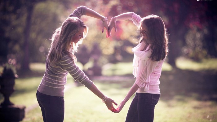 Two Friends Making a Heart Shape with Their Hands Outside