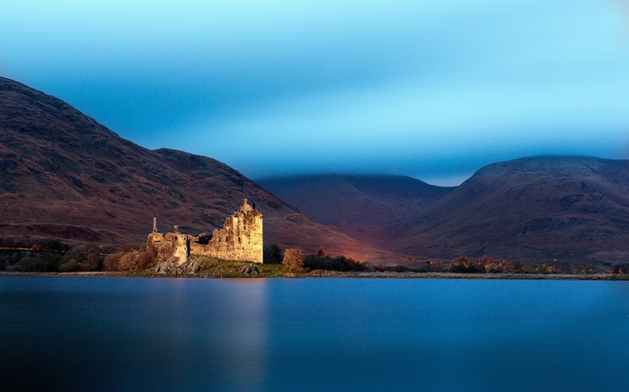 Castle ruins on a lake with mountains