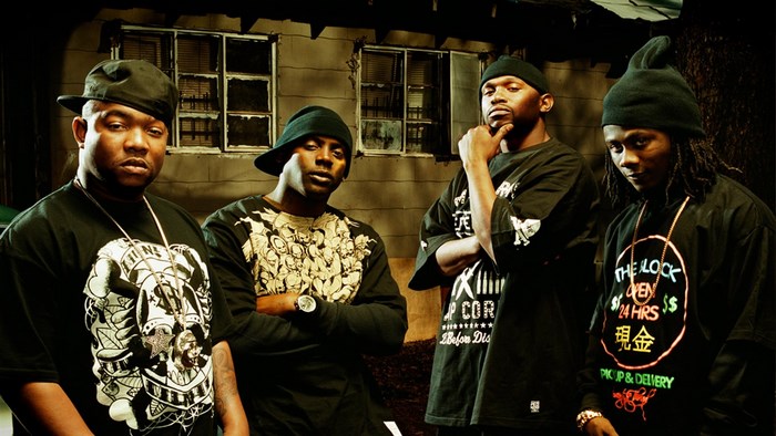 Four men in black beanies and t-shirts