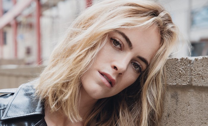 Emily Wickersham leaning on a brick wall