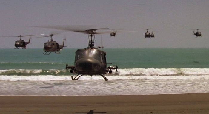 Helicopters flying over the ocean near a beach