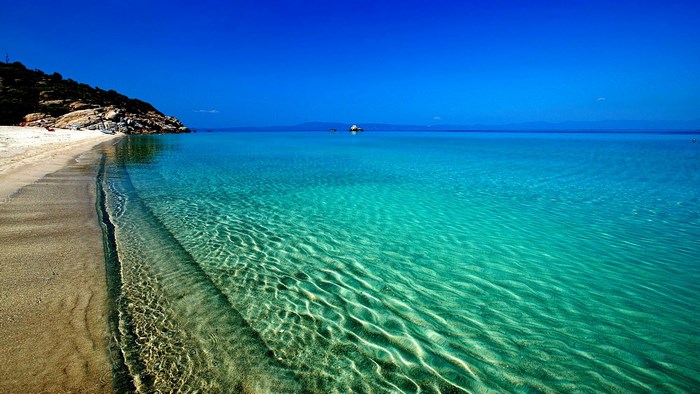 Beach with clear turquoise water and rocky hill