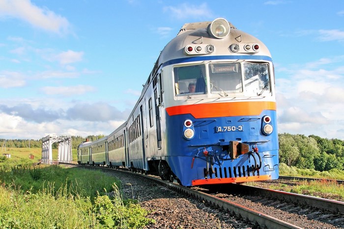 Blue and orange train on tracks with bridge
