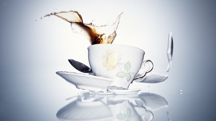Broken teacup with splashing coffee and spoon