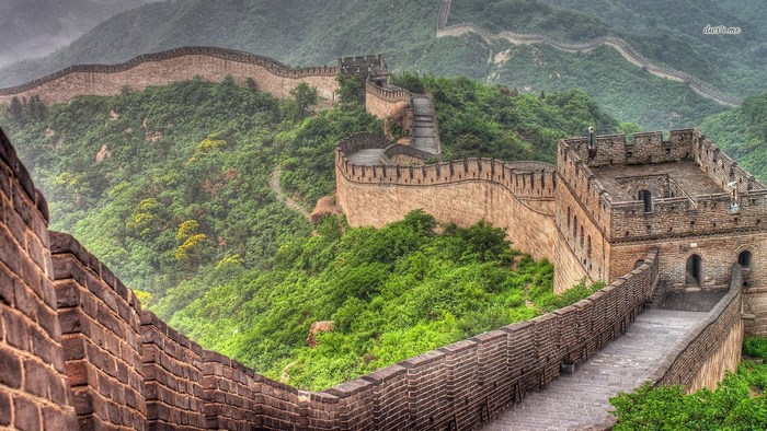 The Great Wall of China winding through green mountains