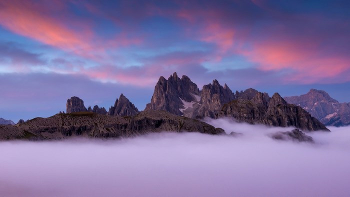 Mountain range above clouds at sunset