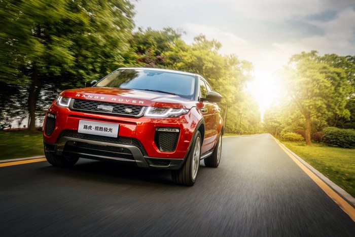 Red Range Rover Evoque driving on a road