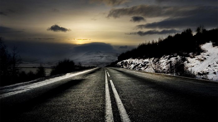 Road through a snowy landscape at sunset