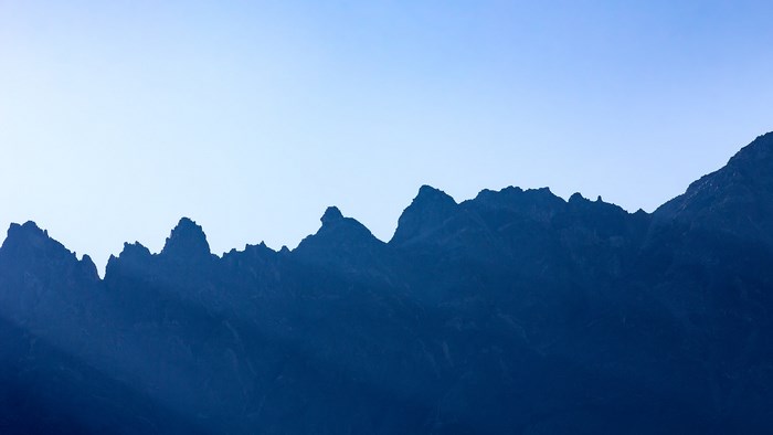 Silhouette of jagged mountain range against clear sky