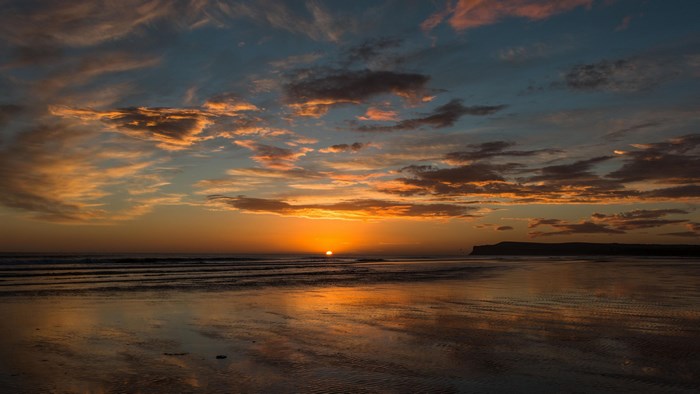 Sunset over a beach with dramatic clouds