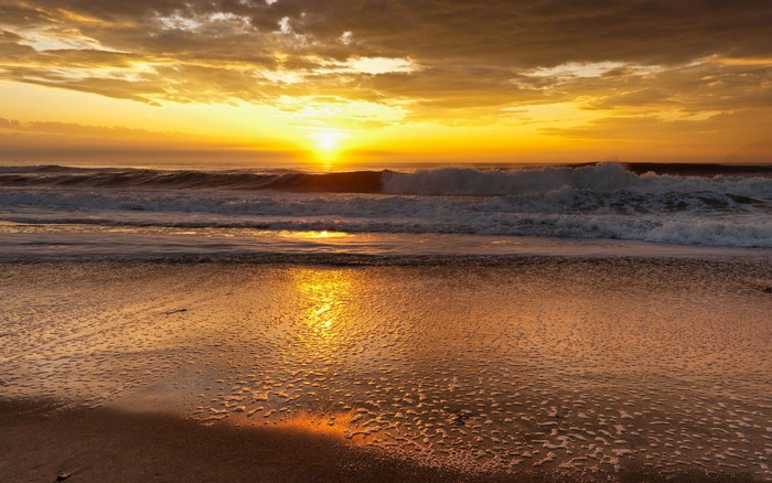 Sunset over the ocean with waves and beach