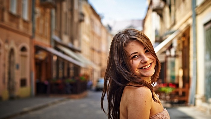 Smiling Woman with Long Brown Hair on City Street