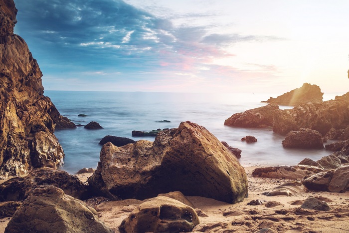 Sunrise over rocky beach with ocean waves