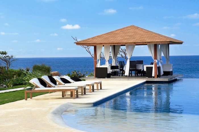 Gazebo and lounge chairs by infinity pool overlooking ocean