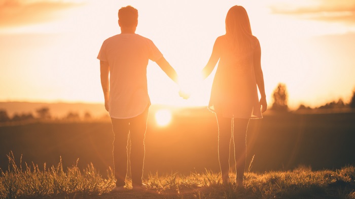 Couple holding hands at sunset 4K