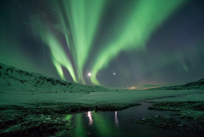 Aurora Borealis over Snowy Landscape with Reflection