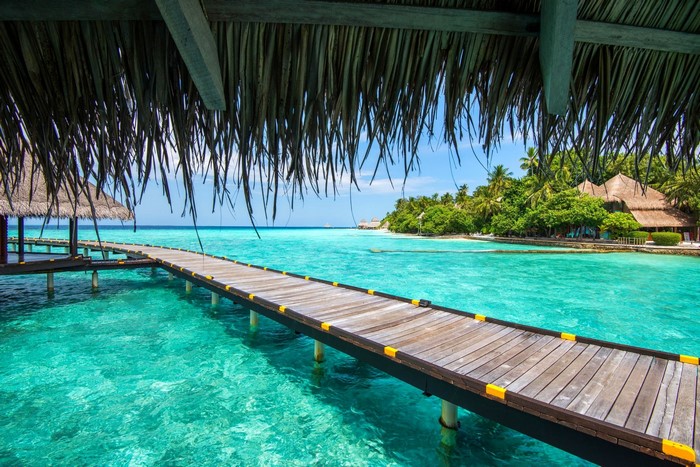 Tropical Maldives resort with wooden walkway over turquoise water