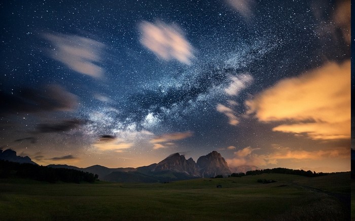 Milky Way over mountains and grassy field