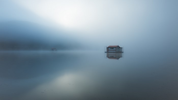 Floating house on a misty lake with reflections