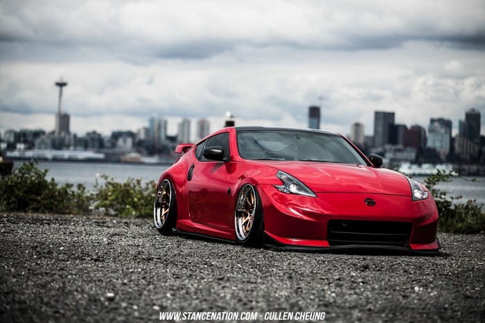 Red Nissan 370Z on gravel with Seattle skyline