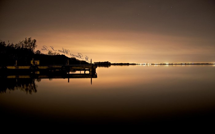 Landscape with dock and distant lights at dusk