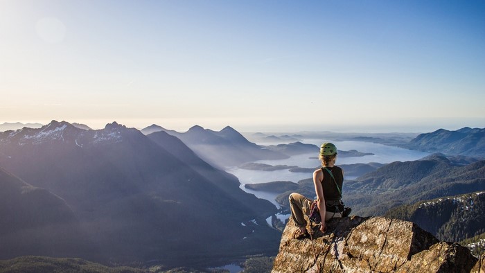 Woman in climbing gear on mountain overlooking lakes