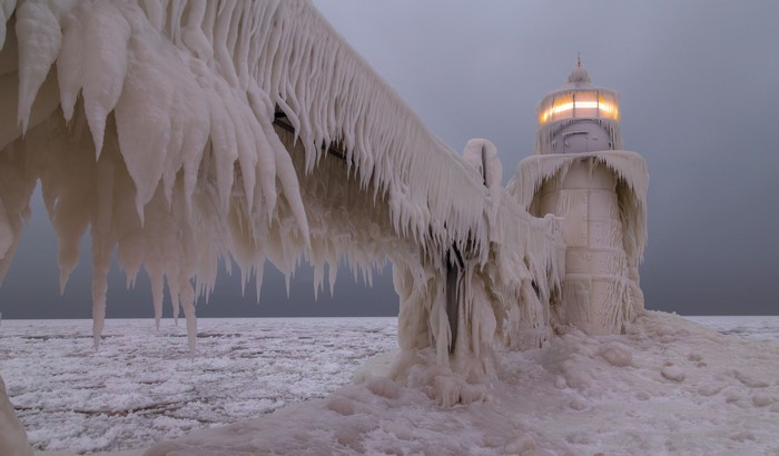 Frozen lighthouse covered in ice during a storm