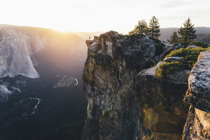 Person standing on a cliff edge at Yosemite National Park during sunset