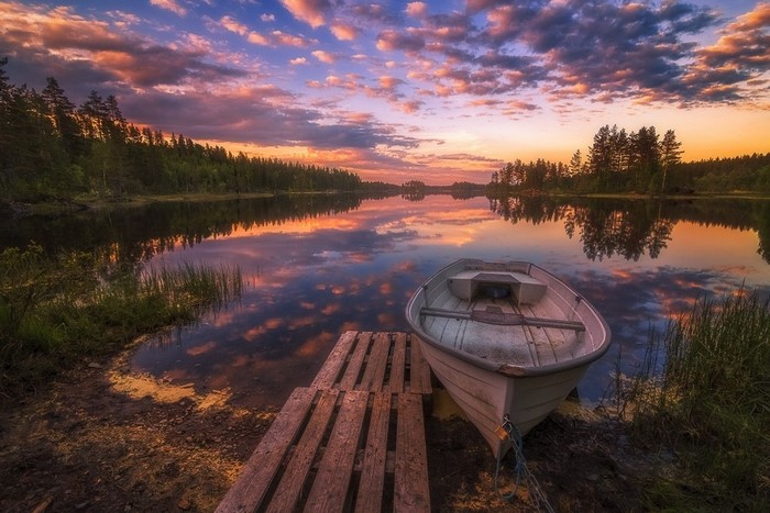Sunset over a lake with a boat and a dock