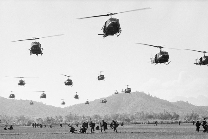 Vietnam War helicopters flying over soldiers in a field
