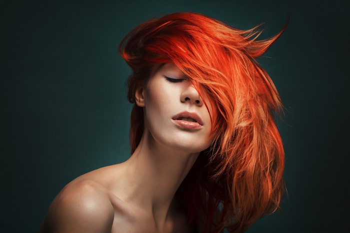 Woman with vibrant red hair and closed eyes