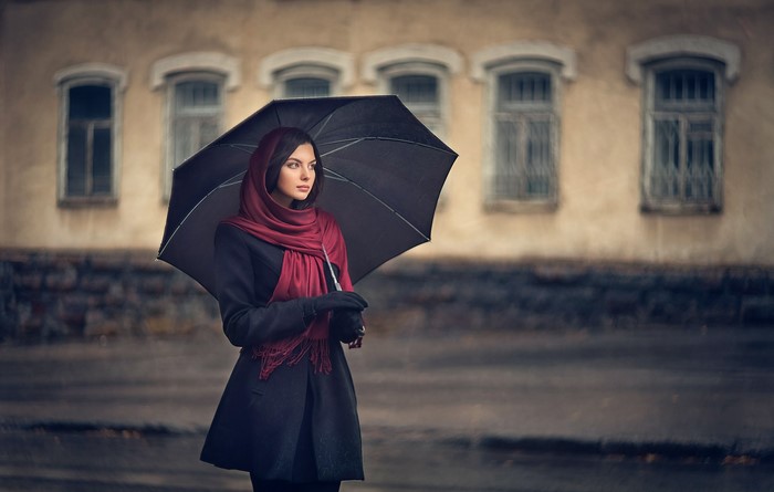 Woman with umbrella in front of building