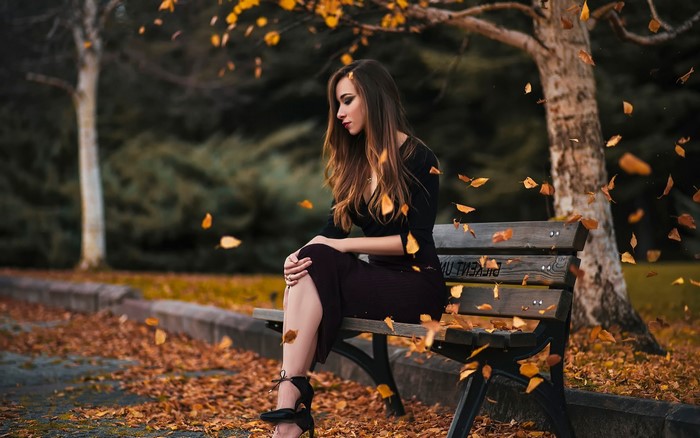 Woman sitting on a park bench in autumn
